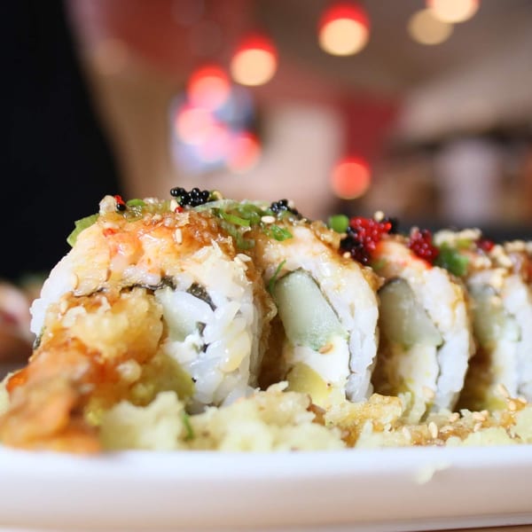 Close-up of Silver Spoon Thai & Sushi's sushi rolls topped with sauce, roe, and sesame seeds.